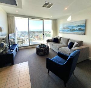 a living room with a couch and chairs and a large window at Colley 11-11 Sub-Penthouse Luxurious Glenelg in Glenelg