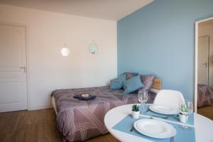een kamer met een bed en een tafel met borden erop bij Home2Stay Valognes in Valognes