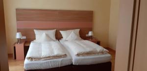 a bedroom with two beds with white sheets and pillows at Linden's Pension-Restaurant in Ayl