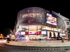 un gran edificio con una fachada curva por la noche en Dominol House l 5 min to Nimman l MAYA l Old Town l 附近的房子, en Chiang Mai