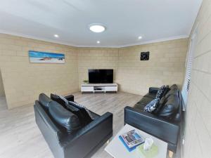 a living room with two leather couches and a tv at Ocean Escape Esperance in Esperance