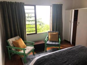 a bedroom with a bed and two chairs and a window at Emma's Beach Cottage in Groot Brak Rivier