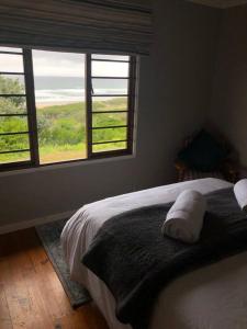 Schlafzimmer mit einem Bett und einem Fenster mit Aussicht in der Unterkunft Emma's Beach Cottage in Groot Brak Rivier