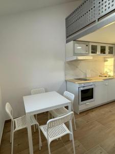 een kleine keuken met een witte tafel en stoelen bij Miniloft Baiona I in Baiona