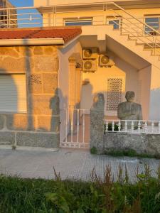 Una statua seduta su una recinzione di fronte a una casa di Miniloft Baiona I a Baiona