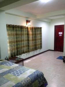 1 dormitorio con 1 cama y una ventana con cortinas en S.K.House 2, en Chiang Mai