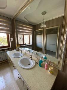 La salle de bains est pourvue de 2 lavabos et d'un grand miroir. dans l'établissement Sultan Sarai Osh, à Och