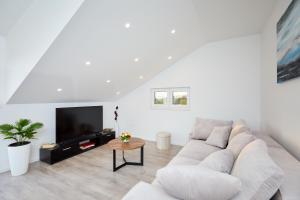 a white living room with a couch and a tv at Mia Maria Apartment in Cavtat