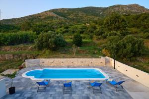 a swimming pool with chairs and a hill in the background at Mia Maria Apartment in Cavtat