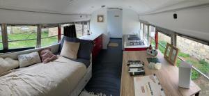 a living room with a bed in a trailer at The School Bus in Bassenge