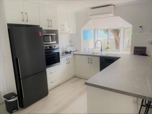 a kitchen with a black refrigerator and white cabinets at Salt & Soul Beach Shack in Esperance