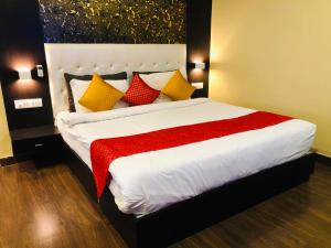 a bedroom with a large bed with red and yellow pillows at Hotel Bhagwati INN Udaipur in Udaipur