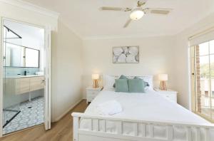 una camera da letto bianca con un letto grande e uno specchio di 10 Minnibah Circuit a Forster