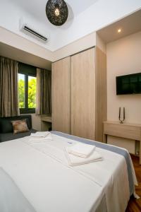 a bedroom with a large white bed and a tv at Thalia by Heloni Apartments in Athens