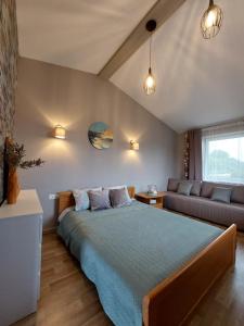 a bedroom with a large bed and a couch at Viesu nams ADLERI in Saldus