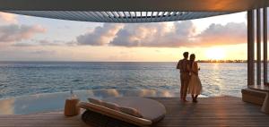 The Ritz-Carlton Maldives, Fari Islands في نورث ماليه آتول: زوجان واقفان على سطح السفينة يراقبان المحيط