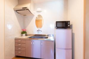 a small kitchen with a sink and a refrigerator at Miyajima Fujinoya Female Only in Miyajima