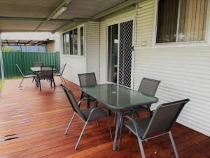 a patio with a table and chairs on a deck at Six By The Beach in Esperance