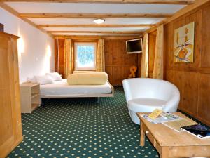 a living room with two beds and a table at Hotel Posta in Sedrun