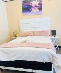 1 dormitorio con 1 cama blanca grande con manta rosa en Affordable Guest Room @260Main en Johannesburgo