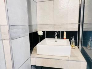 baño con lavabo blanco y flor en Affordable Guest Room @260Main en Johannesburgo