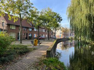 a canal in a town with houses and a bridge at Bijzonder stadshuis met diepe moderne tuin. in Alphen aan den Rijn