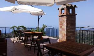 eine Außenterrasse mit Tischen und einem Sonnenschirm in der Unterkunft La Dimora di Ulisse in San Mauro Cilento