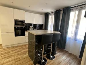 a kitchen with white cabinets and a black counter top at Appartement Gare Saint Charles in Marseille