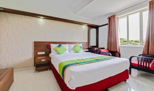 a hotel room with a bed and two chairs at Amala's Residency in Trivandrum