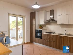 a kitchen with wooden cabinets and a stove top oven at * [Stalettì] *La casa sul mare* in Stalettì