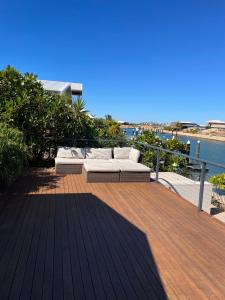 a wooden deck with a couch and a view of the water at Gecko - On the Marina with Pool & Private Jetty in Exmouth