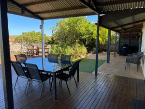 a patio with a table and chairs on a deck at Gecko - On the Marina with Pool & Private Jetty in Exmouth