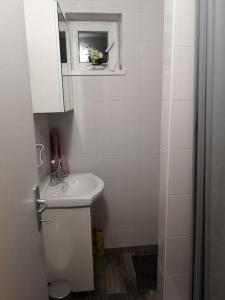 a white bathroom with a sink and a mirror at Apartman studio Otium in Pirovac