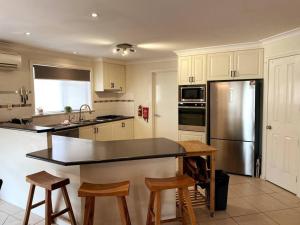 a kitchen with a stainless steel refrigerator and wooden stools at The Sundowner in Esperance
