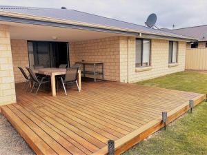 una terraza de madera con mesa y sillas en una casa en The Sundowner, en Esperance