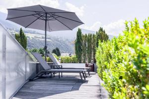 un patio con 2 sillas y una sombrilla en Soley Suites - adults only, en Bresanona