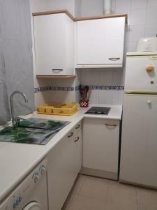 eine weiße Küche mit einer Spüle und einem Kühlschrank in der Unterkunft Apartamento Aretusa Luz in Zahara de los Atunes