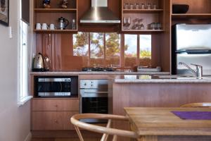 una cocina con armarios de madera y una mesa con sillas. en Orford Panache, en Daylesford