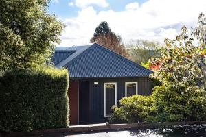 una casa con techo negro y algunos arbustos en Orford Panache, en Daylesford