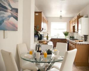 uma cozinha com uma mesa de vidro e cadeiras brancas em City Centre 4 Bedroom-Sleeps 8! em Winchester