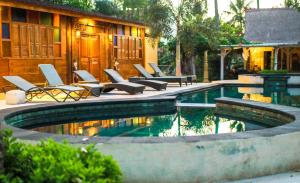 a swimming pool with lounge chairs next to a house at Salim Beach Resort in Gili Air