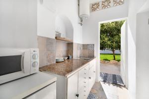 a kitchen with white cabinets and a microwave at Obispo Rancés 12 A in Chiclana de la Frontera
