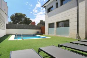 un patio trasero con piscina y césped en Hotel Sitges, en Sitges