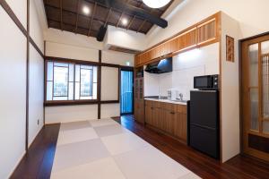 上越的住宿－‐izen 高田‐ 多賀，厨房配有木制橱柜和黑色冰箱。