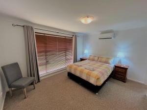 a bedroom with a bed and a chair and a window at The Willow in Esperance