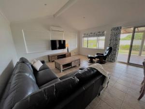 a living room with a black couch and a tv at The Willow in Esperance