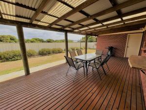 a wooden deck with a table and chairs on it at The Willow in Esperance