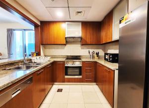 uma cozinha com armários de madeira e um frigorífico de aço inoxidável em RH- The Perfect Family Getaway, 3BR in Standpoint Tower em Dubai