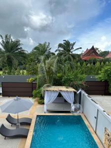 a patio with a pool and a table and an umbrella at Aonang nine poolvilla in Ao Nang Beach