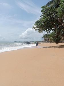 贝鲁沃勒CocoVilla Boutique Resort的一个人在海边的海滩上行走 更多34张照片